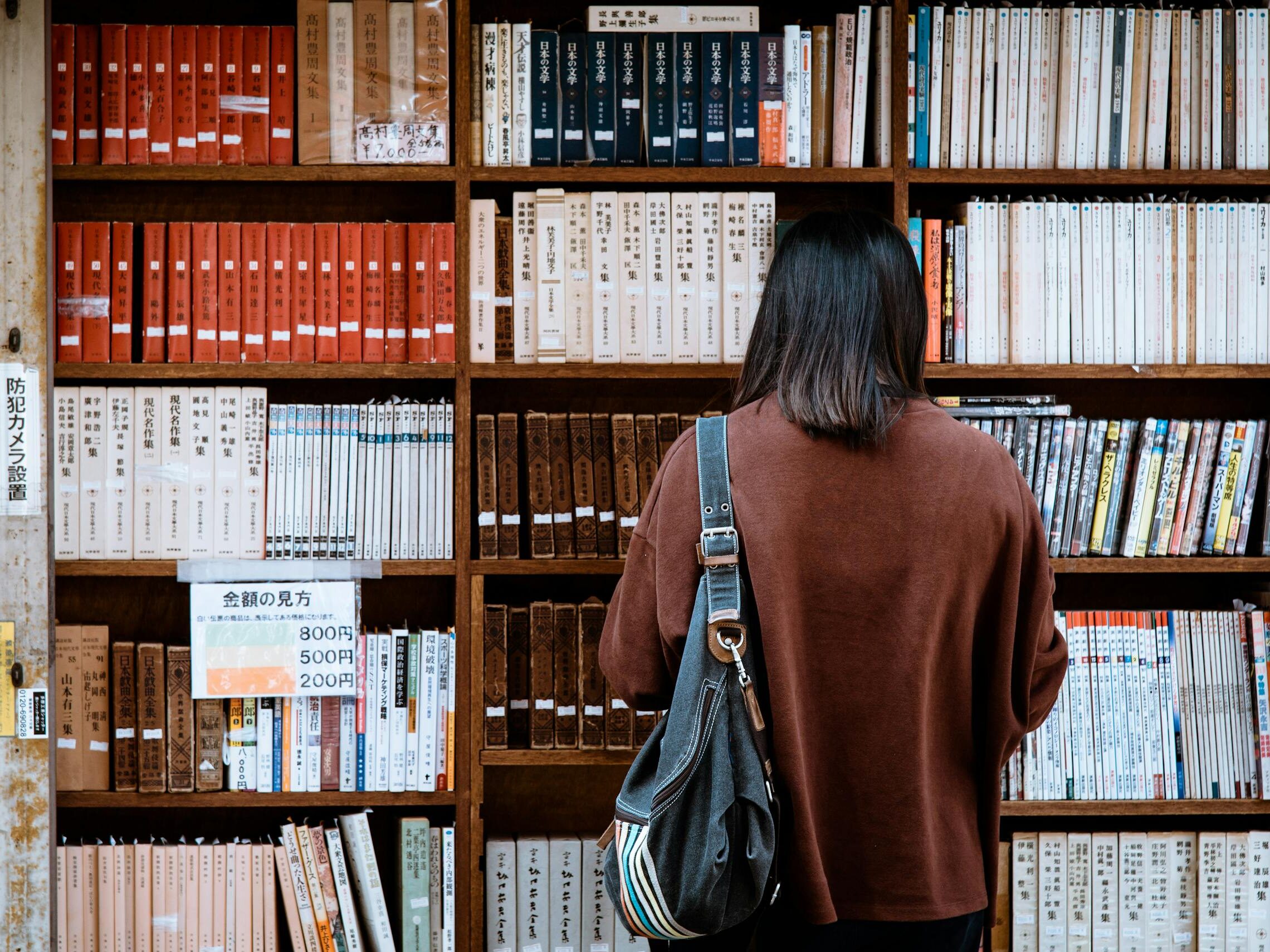Woman browsing books at a library in Nagano, Japan. Explore knowledge and literature.